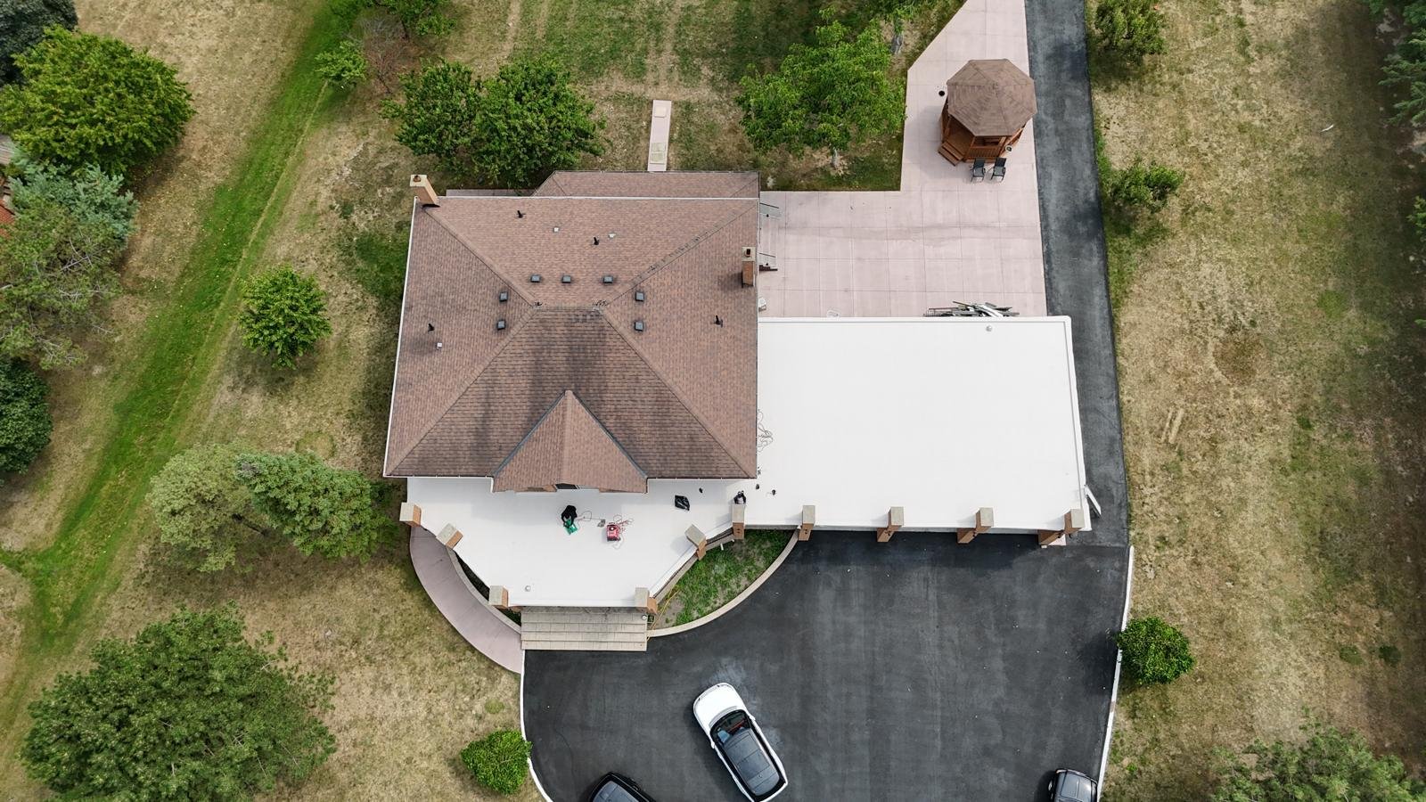 Aerial view of a residential property with shingle and flat roof sections