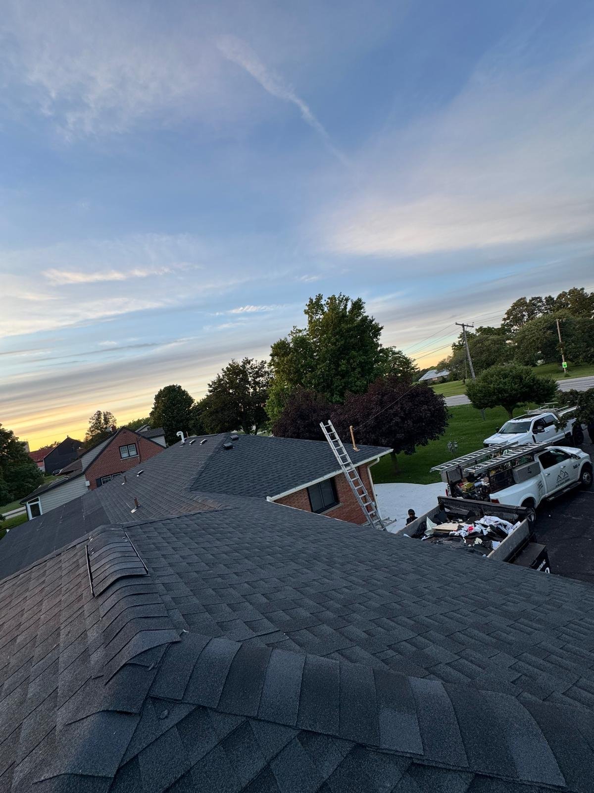 Completed shingle roof on a residential property at sunset